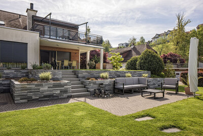 garten_mit_terrasse_sitzgruppe_und_steintreppen_umgeben_von_Natursteinmauer_gartenanlagen_und_vegetation