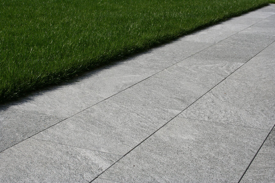 natursteinplatten_aus_calanza_als_bodenbelag_vor_grünem_rasen