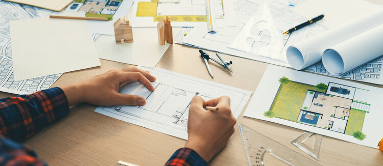 planung_von_umgebung_mit_skizzen_auf_pult_und_hausmodell