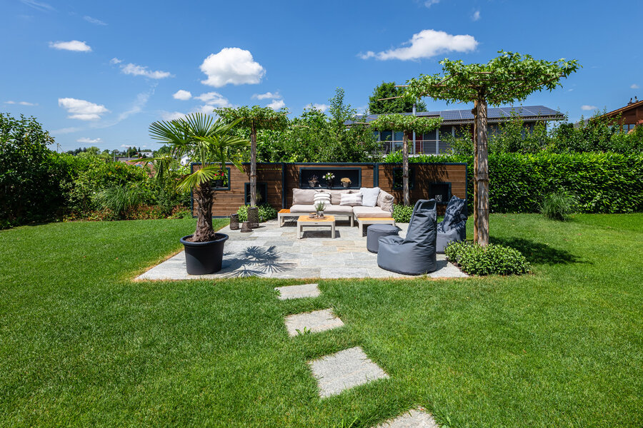 garten_mit_sitzbereich_und_pflanzenbeeten_und_sichtschutzwand aus_impraegniertem_holz_von_impraegnierwerk_willisau_und_natursteinplatten_luserna_von_naturastein_zell