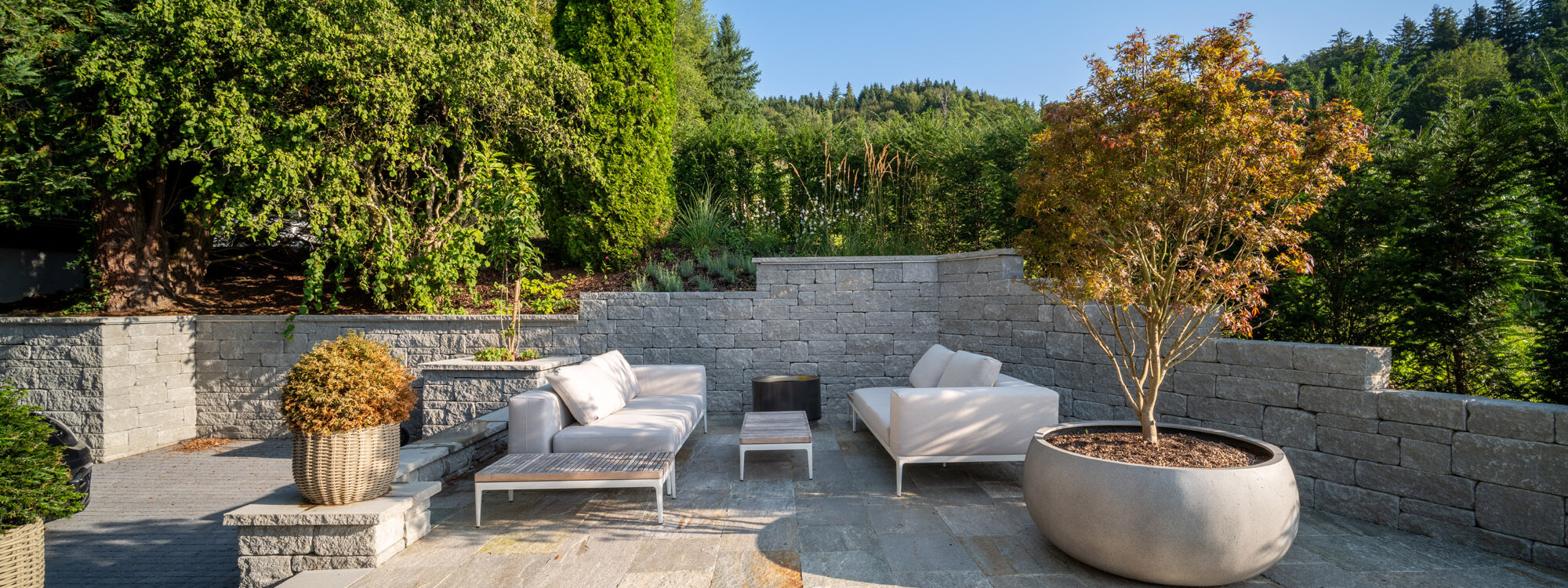 garten_loungebereich_mit_stützmauer_aus_santuro_und_grünem_hintergrund_umgeben_von_bepflanzung