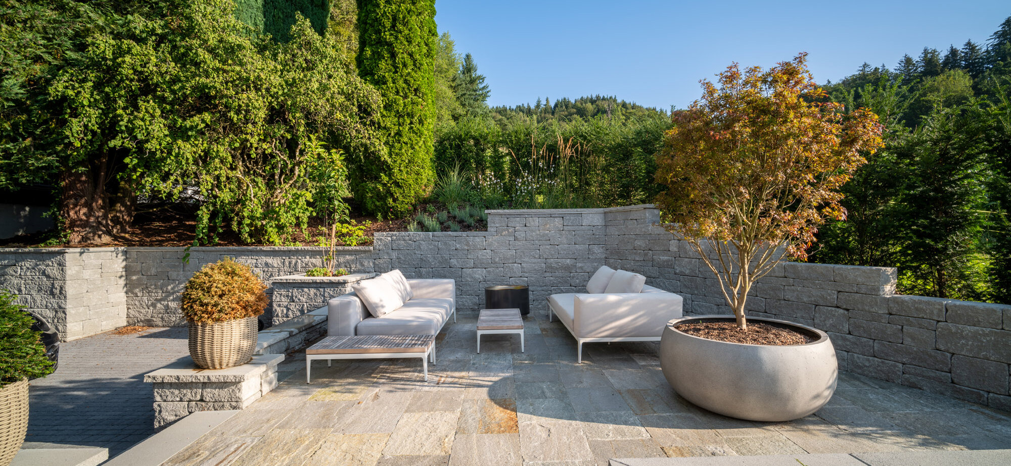 garten_mit_luxuriösem_sitzbereich_eingebettet_in_santuromauern_umgeben_von_hochwachsenden_bäumen_und_grünem_terrain